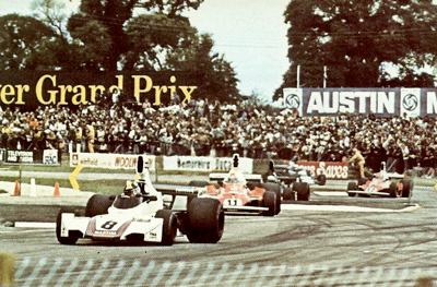 Carlos Pace's Brabham leads a stream of 1975 F1 GP cars through the Woodcote esses